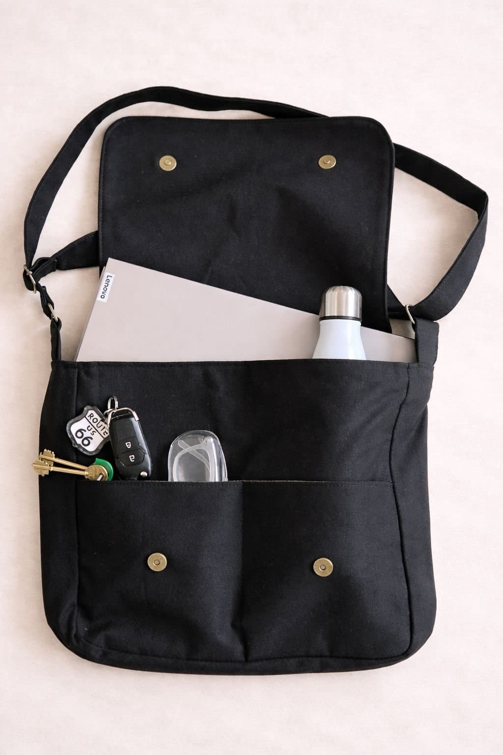 Morral Negro V1 abierto, con una notebook, llaves y una botella